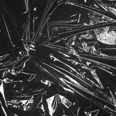 Kırışıklıklar ve kıvrımlar üzerindeki ışığı ve gölgeyi siyah plastik kaplamayla yansıtıyor. monokrom ışık ve doku, soyut arkaplan resmi.