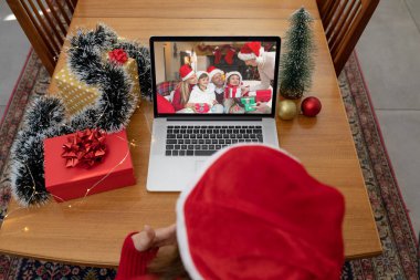 Kafkasyalı bir kadın, Kafkasyalı bir aileyle yılbaşı dizüstü bilgisayarında video görüşmesi yapıyor. Noel, şenlik ve iletişim teknolojisi.