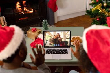Noel Baba şapkalı Afrikalı çift arkadaşlarıyla birlikte dizüstü bilgisayarda Noel Baba 'yı arıyor. Noel, şenlik ve iletişim teknolojisi.