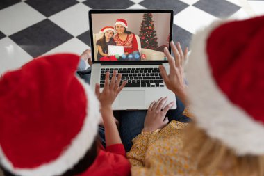 Noel Baba şapkalı Afrikalı anne ve çocuk arkadaşlarıyla birlikte dizüstü bilgisayardan Noel Baba 'nın video çağrısını izliyorlar. Noel, şenlik ve iletişim teknolojisi.