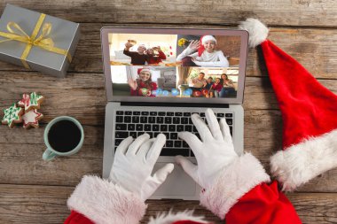 Laptop 'taki Noel Baba' nın elleri gülümseyen arkadaşlarla Noel videosu görüşmesi yapıyor. Noel, şenlik ve iletişim teknolojisi.
