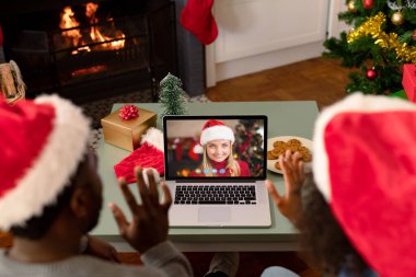 Noel Baba şapkalı Afro-Amerikan çift, kız arkadaşıyla Noel 'de görüntülü görüşme yapıyor. Noel, şenlik ve iletişim teknolojisi.