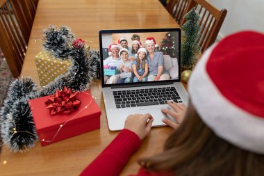 Kafkasyalı bir kadın, Kafkasyalı bir aileyle yılbaşı dizüstü bilgisayarında video görüşmesi yapıyor. Noel, şenlik ve iletişim teknolojisi.