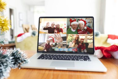 Mutlu Kafkasyalı aile üyeleri Noel zamanı dizüstü bilgisayar grubu görüntülerine el sallıyor. Noel, şenlik ve iletişim teknolojisi.