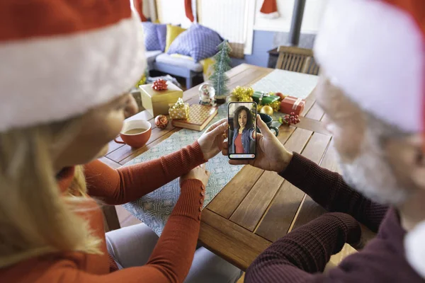 戴着圣诞礼帽的白种人夫妇和笑着的女性朋友打了圣诞智能手机视频电话 圣诞节 节日和通信技术 — 图库照片