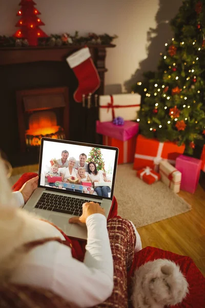 圣诞老人坐在扶手椅上 打字用的手提电脑在家里 在客厅里 — 图库照片