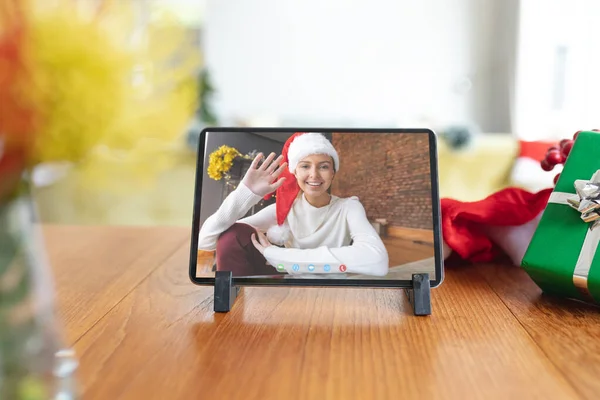 クリスマスの時間にタブレットのビデオ通話画面に手を振ってサンタの帽子の幸せな白人女性 クリスマスやお祭りや通信技術は — ストック写真