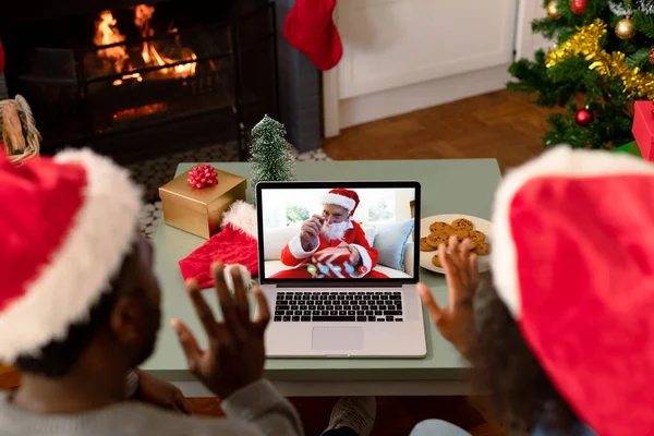 与身穿圣塔服装的老年男子一起 正在为非洲裔美国夫妇制作笔记本电脑圣诞视频通话 圣诞节 节日和通信技术 — 图库照片