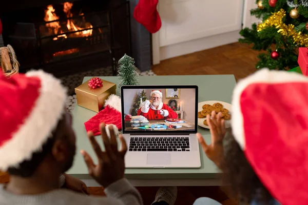 アフリカ系アメリカ人のカップルがサンタの笑顔でノートパソコンのクリスマスビデオ通話を作っています クリスマスやお祭りや通信技術は — ストック写真