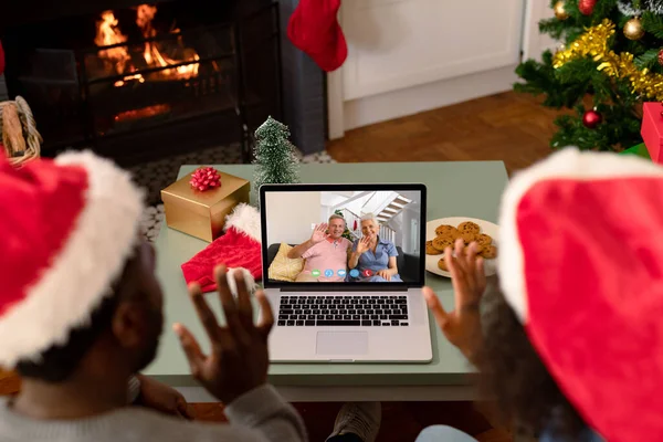 非洲裔美国夫妇与高加索裔老年夫妇在笔记本电脑上做圣诞视频通话 圣诞节 节日和通信技术 — 图库照片