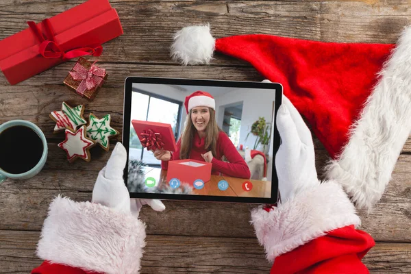 サンタはタブレットを持っていて 笑顔の白人女性が贈り物を開くクリスマスビデオ通話をしています クリスマスやお祭りや通信技術は — ストック写真