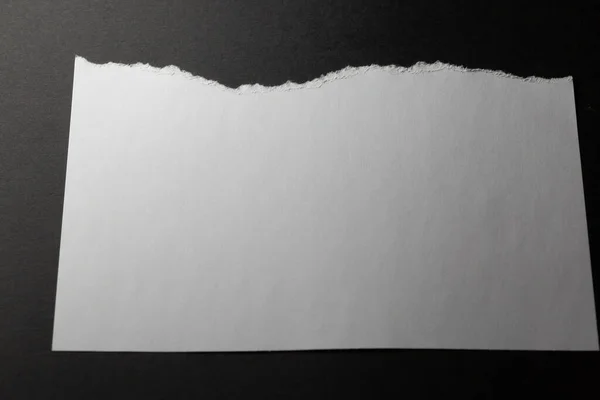 白纸水平薄片 顶部边缘撕破 底色为黑色 单色光和纹理 抽象背景图像 — 图库照片