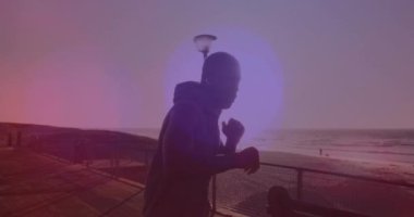 Sahilde koşan ve yumruk atan Afro-Amerikan bir adamın üzerindeki beneklerin canlandırması. sağlık ve zindelik kavramı dijital olarak oluşturulmuş video.