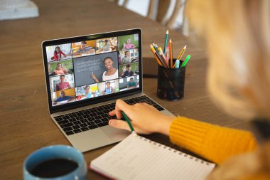 Beyaz bir kadın ekranda çeşitli ilkokul öğrencilerinin gülümsediği bir video görüşmesi için dizüstü bilgisayar kullanıyor. iletişim teknolojisi ve çevrimiçi eğitim, dijital kompozit resim.