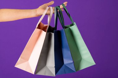 Mavi arka planda el ele alışveriş torbalarının bileşimi. Perakende, alışveriş ve Kara Cuma konsepti.