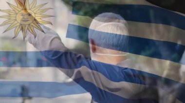 Şehir caddesinde yüz maskesi takan beyaz bir adamın üzerinde dalgalanan Uruguay bayrağının animasyonu. covid 19 salgın konsepti boyunca dijital olarak üretilen küresel sağlık önlemleri.