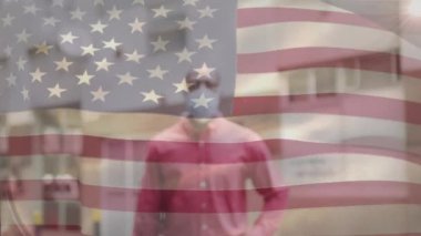 Amerikan bayrağının şehir caddesinde maskeli Afro-Amerikan bir adamın üzerinde dalgalanmasının animasyonu. covid 19 salgın konsepti boyunca dijital olarak üretilen küresel sağlık önlemleri.