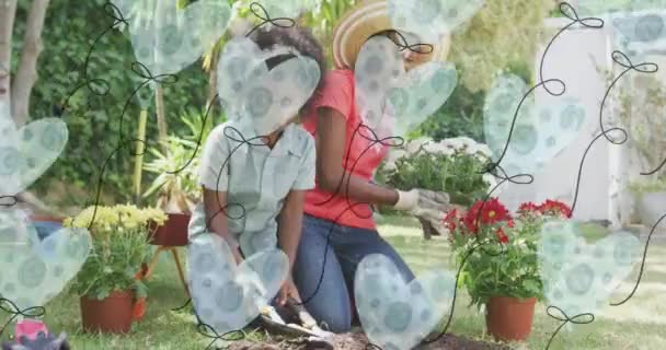 在快乐的非洲裔美国母亲和女儿种植植物的过程中 心脏气球的动画 家庭生活 爱情和照料概念数码视频 — 图库视频影像