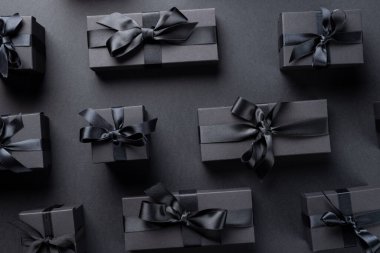 Gri arka planda siyah kurdeleli hediyelerin kompozisyonu. Perakende, alışveriş ve Kara Cuma konsepti.