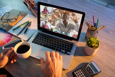 Video görüşmesi için dizüstü bilgisayar kullanan adamın elleri ekranda çeşitli lise öğrencilerini sallıyor. iletişim teknolojisi ve çevrimiçi eğitim, dijital kompozit resim.