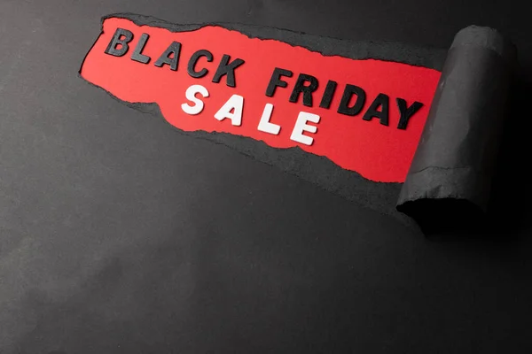 Composition of black paper and black friday sale text on red background. Retail, shopping and black friday concept.