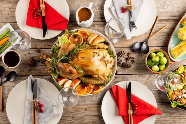 Overhead view of thanksgiving table with roast chicken and vegetables and autumn decoration on wood. Thanksgiving, autumn, fall, american tradition and celebration concept.