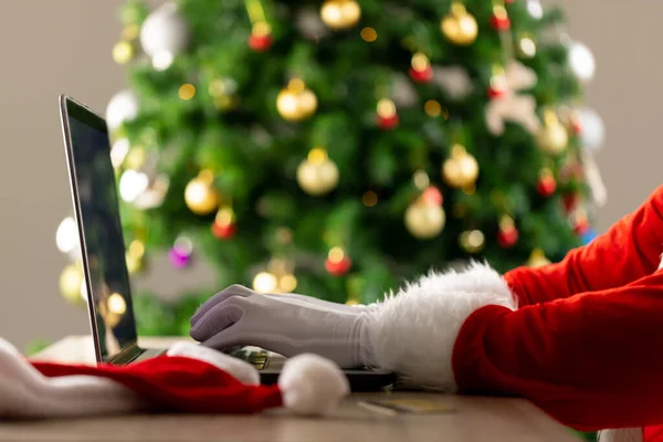 Arka Planda Yılbaşı Ağacı Olan Bir Dizüstü Bilgisayar Kullanan Noel — Stok fotoğraf