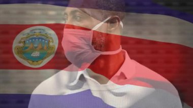 Kosta Rika bayrağının şehir caddesinde maskeli Afro-Amerikan bir adamın üzerinde dalgalanması. covid 19 salgın konsepti boyunca dijital olarak üretilen küresel sağlık önlemleri.