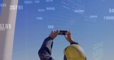 Yel değirmeninin fotoğrafını çeken erkek mühendis üzerinde birden fazla değişen sayının animasyonu. Küresel ekonomi ve yenilenebilir enerji teknolojisi kavramı