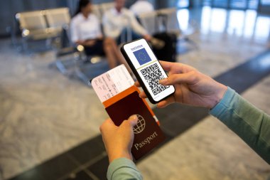Havaalanında elinde belgeler ve elinde 19 aşılı pasaportlu akıllı telefon olan bir kadın var. küresel covid 19 salgın konsepti dijital olarak oluşturulmuş video.