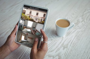 Beyaz kadının elleri ekrandaki güvenlik kameralarından tableti eve doğru tutuyordu. güvenlik, güvenlik, izleme ve dijital arayüz.