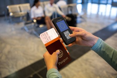 Havaalanında elinde belgeler ve elinde 19 aşılı pasaportlu akıllı telefon olan bir kadın var. küresel covid 19 salgın konsepti dijital olarak oluşturulmuş video.