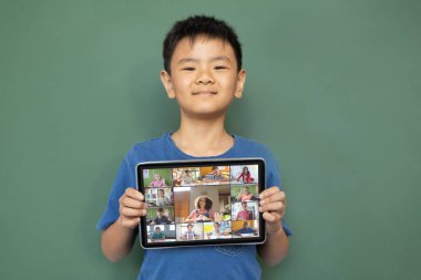 Çeşitli ilkokul öğrencileriyle video görüşmesi için elinde tablet olan gülümseyen Asyalı çocuk. iletişim teknolojisi ve çevrimiçi eğitim, dijital kompozit resim.