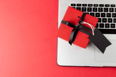 Pembe arka planda hediye etiketli dizüstü bilgisayar kompozisyonu. Perakende, alışveriş ve Kara Cuma konsepti.