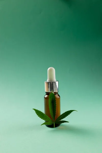 Yeşil Yüzeyde Bir Şişe Cbd Yağı Marihuana Yaprağı Dikey Görüntüsü — Stok fotoğraf