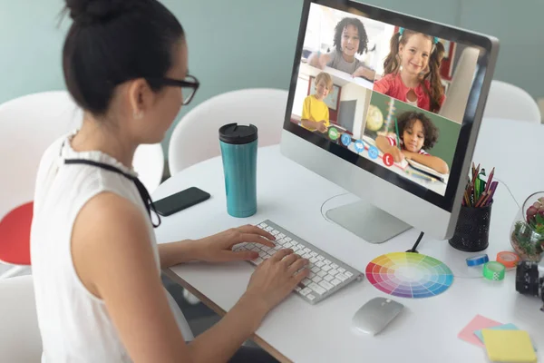 Asian girl holding computer for video call, with smiling diverse elementary school pupils on screen. communication technology and online education, digital composite image.
