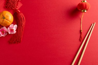 Kırmızı arka planda geleneksel Çin dekorasyonu ve çubuk kompozisyonu. Çin yeni yılı, gelenek ve kutlama konsepti.