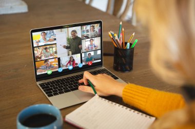 Video görüşmesi için dizüstü bilgisayar kullanan beyaz bir kadın, ekranda çeşitli lise öğrencileri gülümsüyor. iletişim teknolojisi ve çevrimiçi eğitim, dijital kompozit resim.