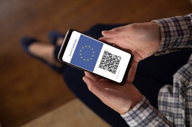 Elinde kovid 19 aşı pasaportlu akıllı telefonu olan bir kadın. küresel covid 19 salgın konsepti dijital olarak oluşturulmuş video.
