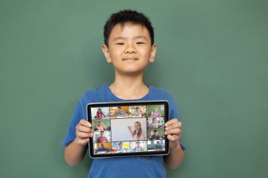 Çeşitli ilkokul öğrencileriyle video görüşmesi için elinde tablet olan gülümseyen Asyalı çocuk. iletişim teknolojisi ve çevrimiçi eğitim, dijital kompozit resim.