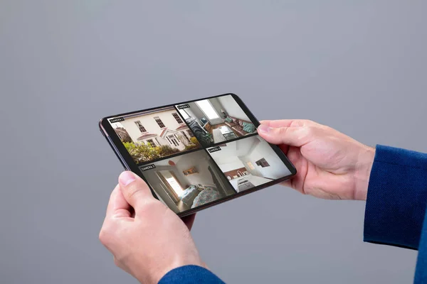 手里拿着平板电脑的高加索人的手 屏幕上的摄像头可以看到家里的风景 监视和数字接口 — 图库照片