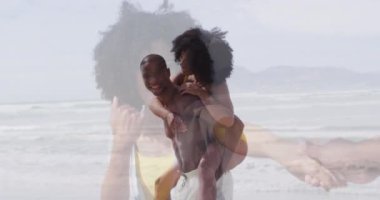 Mutlu Afro-Amerikan çifti, kumsalda, denizden eş çağıran bir kadının sırtından geçiniyor. Tatiller, mutluluk, romantizm ve birliktelik kavramı dijital olarak oluşturulmuş video.