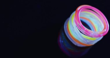 Siyah arkaplan üzerinde çoklu renkli neon ışıklı çubukların fotokopi alanı ile canlandırılması. Arkaplan, telif alanı ve renk kavramı.