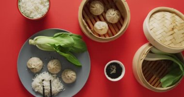 Tabak ve bambu buharlı hamur tatlısı, pak choi ve pilav karışımı kırmızı arka planda. Yiyecek, içecek ve renk konsepti.