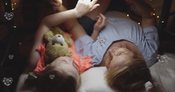 白人の母親と娘の上に心のアニメーションベッドに横たわっていた 家族の生活愛とケアの概念デジタルで生成されたビデオ — ストック動画