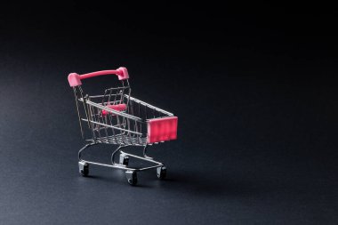 Alışveriş arabasının kompozisyonu ve gri arka planda fotokopi alanı. Perakende, alışveriş ve Kara Cuma konsepti.