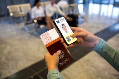 Havaalanında elinde belgeler ve elinde 19 aşılı pasaportlu akıllı telefon olan bir kadın var. küresel covid 19 salgın konsepti dijital olarak oluşturulmuş video.