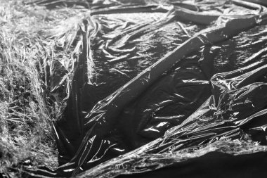 Koyu gri arka planda plastik folyo içinde ışık ve gölgeyi yansıtır ve kıvrılır. monokrom ışık ve doku, soyut arkaplan resmi.