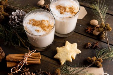 Bir bardak noel sütü, üzerinde tarçın çubukları ve tahtada noel süsü. Noel, gelenek ve kutlama konsepti.