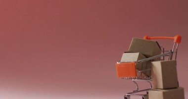 Karton kutularla dolu alışveriş arabasının videosu ve pembe arka planda fotokopi alanı. Siber Pazartesi, Kara Cuma, perakende, alışveriş ve tasarruf kavramı.